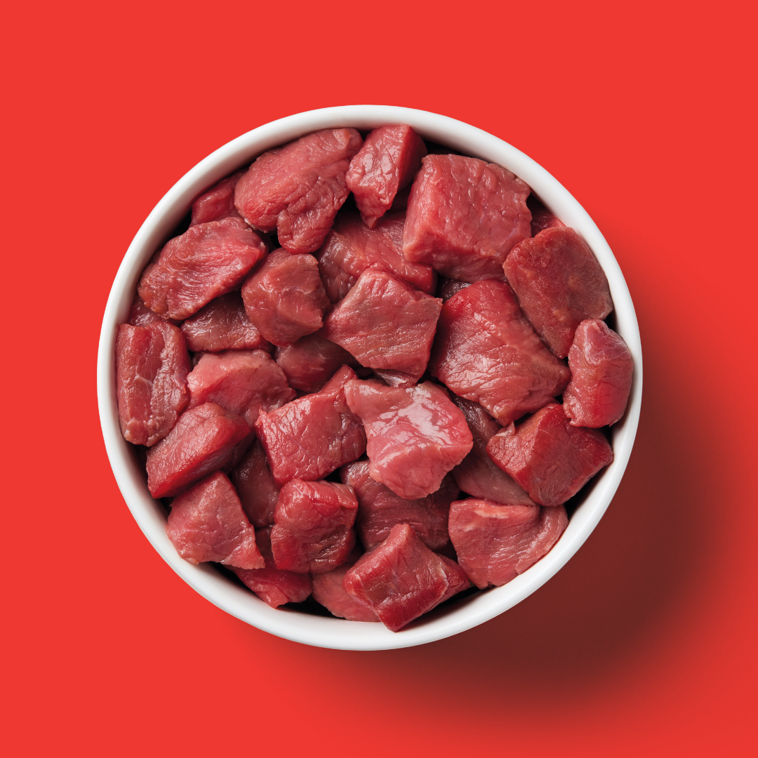 A bowl of Cat Raw Beef 500g diced against a solid red background.