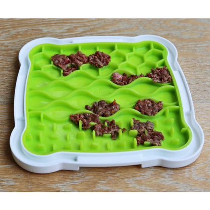 Lick n Snack Licking Plate with dog food spread in compartments for enrichment, on a wooden surface.