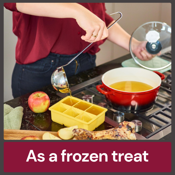 Someone fills a yellow ice cube tray with Beef Bone Broth 500ml next to a red pot. An apple is on the counter.