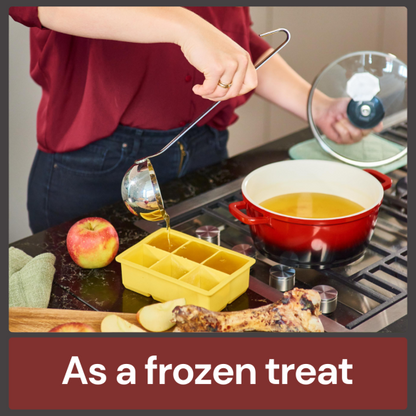 Person pouring Chicken Bone Broth 500ml into a yellow ice cube tray, an apple nearby, on a black countertop.