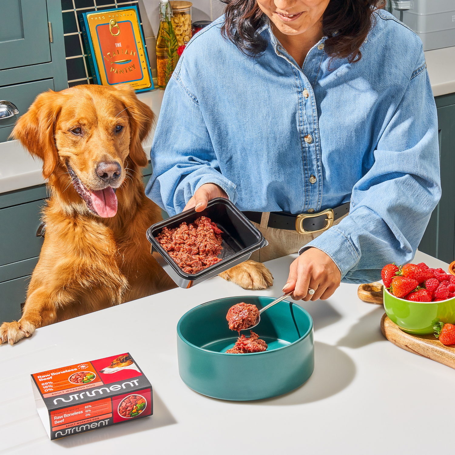 Golden Retriever watching their owner scoop raw food into a bowl in their kitchen