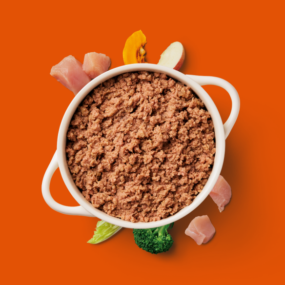 Gently Steamed Chicken 395g with minced meat and raw dog veggies on an orange background.